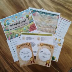 Ausgedruckte Materialien für eine Schnipseljagd für Kinder von 3-6 Jahren. Das Set enthält ein bunt gestaltetes Deckblatt mit Regenbogen und Sternen, eine Elternanleitung mit Erklärungen zur Durchführung, eine Liste mit möglichen Verstecken, eine Spielanleitung zum Schnipseljagd-Prinzip sowie zwei Urkunden für die teilnehmenden Kinder. Die Schnipseljagd bietet 50 Hinweise für drinnen und draußen, die Kinder auf eine spielerische Schatzsuche führen.