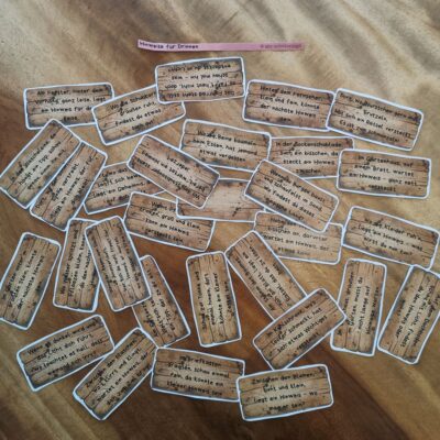Ausgeschnittene Hinweis-Karten für eine Schnipseljagd in Innenräumen. Die Karten haben ein rustikales Holzdesign und enthalten verschiedene Rätsel und Reime, die Kinder von einem Versteck zum nächsten führen. Die Hinweise beziehen sich auf Alltagsgegenstände und Orte im Haus, wie den Fernseher, die Sockenschublade oder den Kleiderschrank, und machen die Schatzsuche spannend und interaktiv