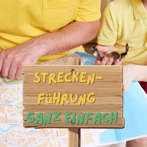 Ein Vater und sein Kind planen mit einer Karte und einem Kompass eine Route für eine Schnitzeljagd. Im Vordergrund steht ein Holzschild mit der Aufschrift 'Streckenführung – Ganz einfach